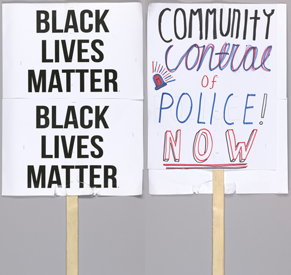  Alt text: One side of the placard reads “Community control of police now”. The word "community" is written in black; "control" is written in red and blue and in cursive; "police" is written in blue; "now" is written in black and red block letters and is underlined twice. The other side of the placard is white with black repeating text that reads “Black Lives Matter Black Lives Matter”. The poster board used for this side of the placard is larger than the other side. The placard is torn and the bottom and worn from use. 