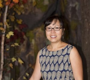 A photo of an asian woman standing outdoors with a patterned sleeveless top.